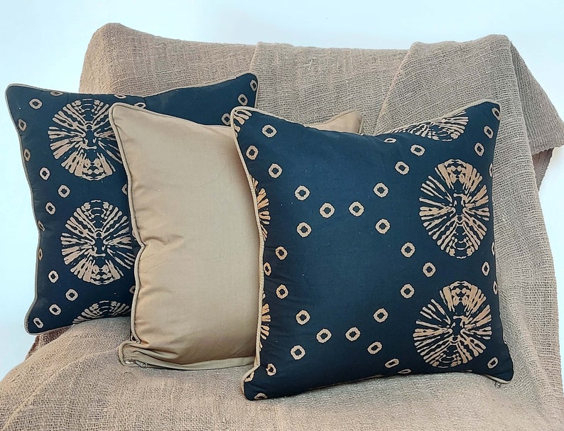 May include: Four throw pillows with a black background and a brown geometric pattern. The pillows are arranged on a brown textured surface.
