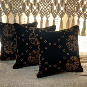 May include: Three black throw pillows with a gold and black geometric pattern. The pillows have a brown trim.
