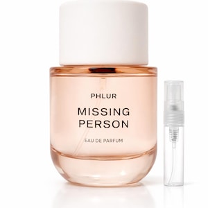 May include: A perfume bottle and a sample vial. The perfume bottle is a rounded rectangle with a white cap. The bottle is filled with a light pink liquid. The text "PHLUR MISSING PERSON EAU DE PARFUM" is printed on the bottle.