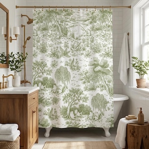 May include: A white shower curtain with a green toile pattern featuring frogs in a forest scene. The design includes trees, plants, and a river. The curtain is hanging in a bathroom with a wooden vanity and a white bathtub.