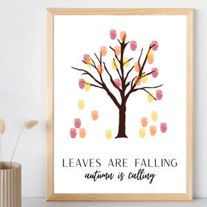 May include: A framed print featuring a dark brown tree silhouette with colorful fingerprint leaves in shades of red, orange, and yellow. The text reads LEAVES ARE FALLING autumn is calling in black capital and script lettering on a white background.