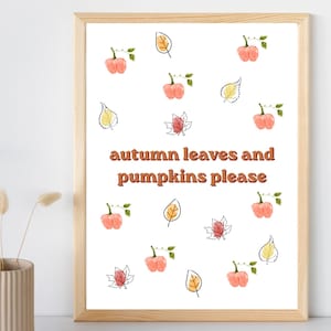 May include: A framed wall art print featuring a white background with a repeating pattern of small watercolor-style orange pumpkins and various autumn leaves in yellow, orange, and red. The text "autumn leaves and pumpkins please" is centered.