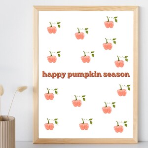 May include: A framed wall art print featuring a repeating pattern of watercolor-style light orange pumpkins with green stems and leaves, centered with the text "happy pumpkin season" in a bold, dark orange, retro-inspired sans-serif font.