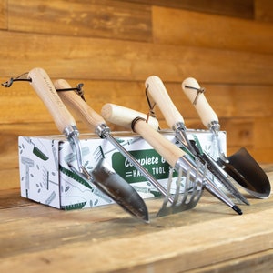 May include: A complete hand tool set with wooden handles and metal blades. The set includes a trowel, cultivator, hand fork, and a small shovel. The tools are arranged in front of a box with the text "Complete Hand Tool Set".