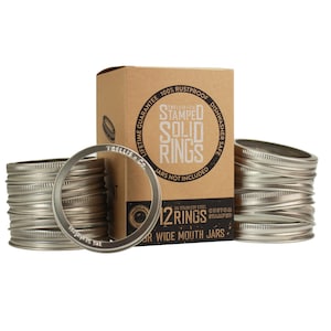 May include: A box of 12 stainless steel, custom stamped, wide mouth jar rings. The box is brown with black text that reads "Trellis Co. Stamped Solid Rings". The rings are stacked in two piles.