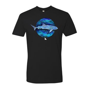 K&ouml;nnte beinhalten: Schwarzes T-Shirt mit einer blauen und wei&szlig;en Illustration eines Walhais, der in einem Kreis aus blauem und wei&szlig;em Wasser schwimmt.