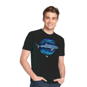 K&ouml;nnte beinhalten: Ein schwarzes T-Shirt mit einem blauen und gr&uuml;nen Kreis-Motiv eines Walhais, der im Ozean schwimmt.
