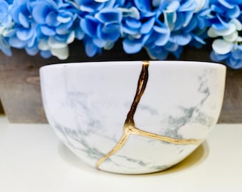 May include: White ceramic bowl with a marble pattern and gold crackle design.