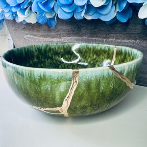 May include: A green ceramic bowl with gold crackle lines. The bowl has a light green glaze and is slightly iridescent.