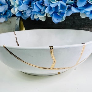 Puede incluir: Tazón de cerámica blanco con diseño de craquelado dorado. El tazón es grande y de forma ovalada.