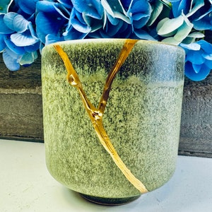 May include: A green ceramic planter with a gold crackle design. The planter has a wide mouth and a rounded bottom.