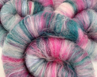 Könnte beinhalten: Nahaufnahme eines Wollknäuels in den Farben Rosa, Türkis, Weiß und Grau. Die Wolle ist weich und flauschig und perfekt zum Stricken oder Häkeln.