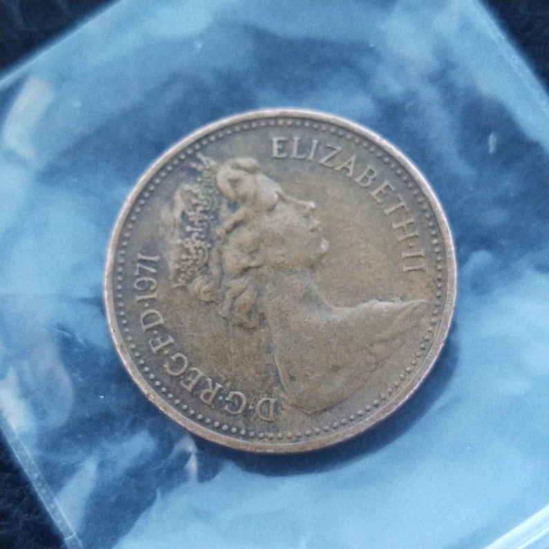 May include: A bronze-colored coin with the inscription "D.G.REG.F.D. 1971" and "ELIZABETH II" around the edge.