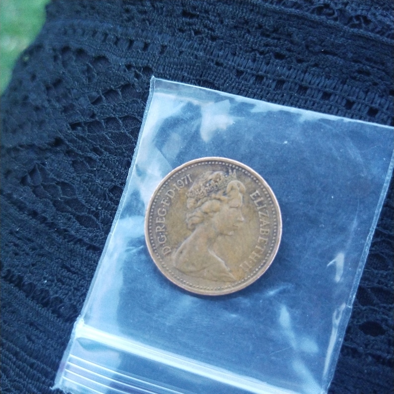 May include: A copper-colored coin with the inscription "D.G. REG. F.D. 1971" and "ELIZABETH II" around the edge.