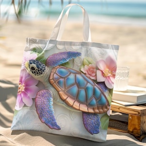 Puede incluir: Bolso tote blanco con una ilustración de tortuga marina. La tortuga tiene un caparazón azul y marrón, rodeada de flores rosas y moradas. El bolso tiene asas blancas y está sobre una playa de arena.