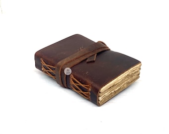 May include: A brown leather-bound journal with a leather strap closure. The journal has a rustic, vintage look and is perfect for writing down thoughts, ideas, or stories.
