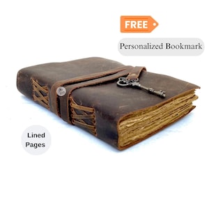 May include: A brown leather journal with lined pages, secured by a leather strap and a decorative key clasp. The journal has a rustic, vintage appearance. The text "Lined Pages" is visible.