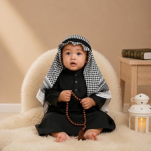 May include: A black long-sleeved thobe worn with a black and white checkered keffiyeh head covering. The garment features a button-down collar and is paired with a string of brown prayer beads held in the hands.
