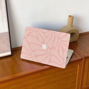 Könnte beinhalten: Ein rosa Laptop mit einem floralen Muster auf dem Deckel. Der Laptop steht auf einem Holztisch.