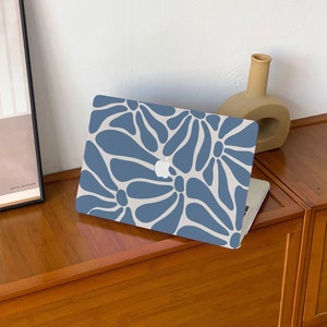 May include: A laptop computer with a blue and white floral pattern on the case. The laptop is closed and sitting on a wooden surface.