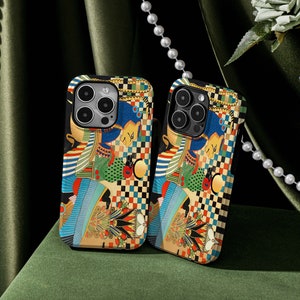 以下が含まれることがあります： チェック柄と模様のデザインが施された、女王と他のキャラクターが描かれたカラフルな携帯電話ケース2つ。ケースは黒い縁取りとカメラの切り抜きがあります。