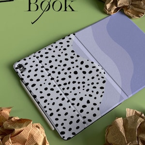 May include: A white and black patterned iPad case with a light blue and white patterned cover. The case is open and the cover is folded back. The word "Book" is written in black on a green background.