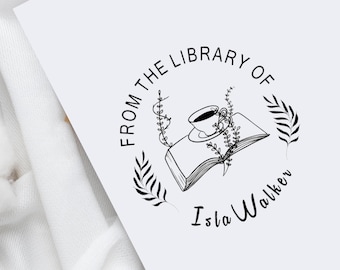 Può includere: Illustrazione in bianco e nero di un libro con una tazza di caffè in cima, circondata da foglie. Il testo "From the Library of Isla Walker" è scritto in un cerchio attorno al libro.