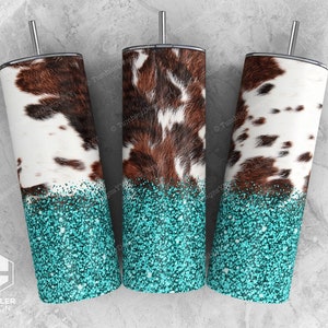 May include: Three stainless steel tumblers with a cowhide pattern and turquoise glitter bottoms. Each tumbler has a silver straw and a black lid. The cowhide design features brown and white patches.