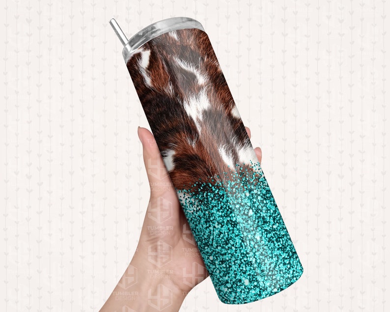 May include: A stainless steel tumbler with a cowhide pattern and a turquoise glitter bottom. The tumbler has a silver straw and a silver lid. The design is a mix of rustic and glam.