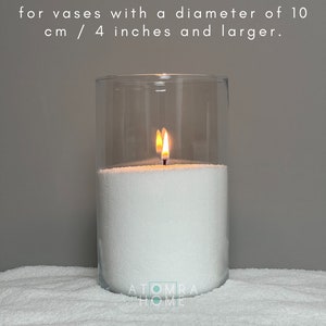 May include: A white candle burning in a clear glass jar. The candle is sitting on a white surface. The text "MEDIUM wicks: recommended for vases with a diameter of 10 cm / 4 inches and larger." is displayed above the candle.