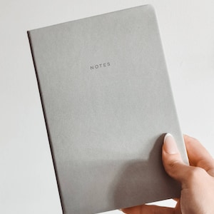 May include: A grey notebook with the word "NOTES" printed on the front cover.