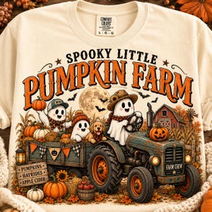 Puede incluir: Una camiseta color crema con un gráfico de dos fantasmas y un cachorro en un tractor tirando de un remolque lleno de calabazas. El texto dice SPOOKY LITTLE PUMPKIN FARM, PUMPKINS, HAYRIDES, APPLE CIDER y FARM CREW. El diseño incluye un granero.