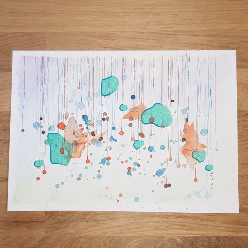 My handmade unique abstract mixed media work called Rain. Blue, metallized green and orange shades like rain drops. Placed on a wooden table.