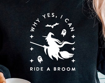 May include: Black sweatshirt with a white graphic of a witch riding a broom. The graphic includes the text "Why yes, I can ride a broom".