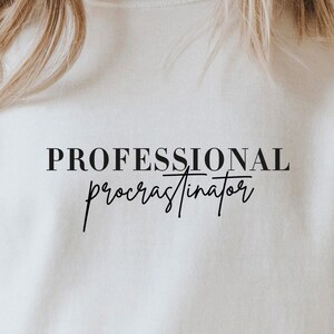 May include: White sweatshirt with black text that reads "PROFESSIONAL procrastinator".
