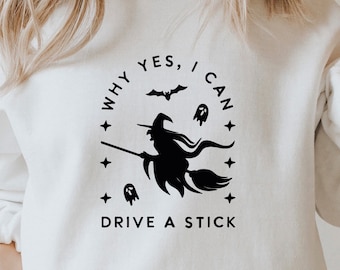 May include: White sweatshirt with a black graphic of a witch flying on a broomstick with the text "Why yes, I can drive a stick".