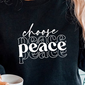 May include: Black sweatshirt with white text that reads "choose peace" in a retro font.