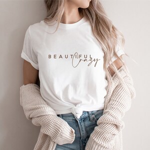 May include: White t-shirt with the text "BEAUTIFUL crazy" printed in brown on the front.