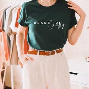 May include: A dark green t-shirt with the text "BEAUTIFUL Crazy" in white lettering.
