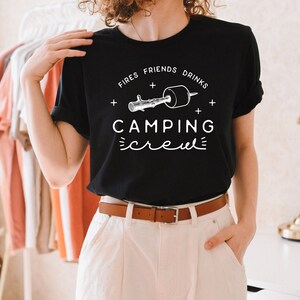 May include: Black t-shirt with white text that reads "Fires + Friends + Drinks + Camping Crew" and a graphic of a stick with a marshmallow on the end.