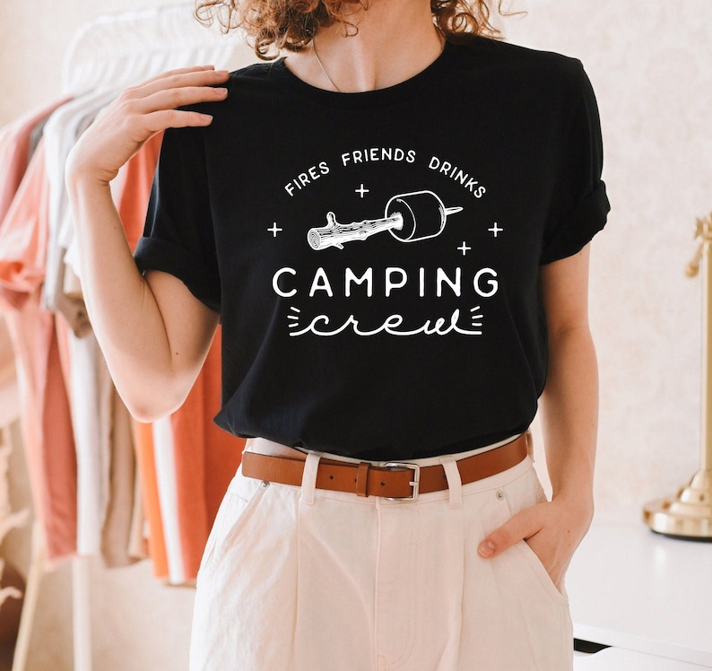May include: Black t-shirt with white text that reads "Fires + Friends + Drinks + Camping Crew" and a graphic of a stick with a marshmallow on the end.