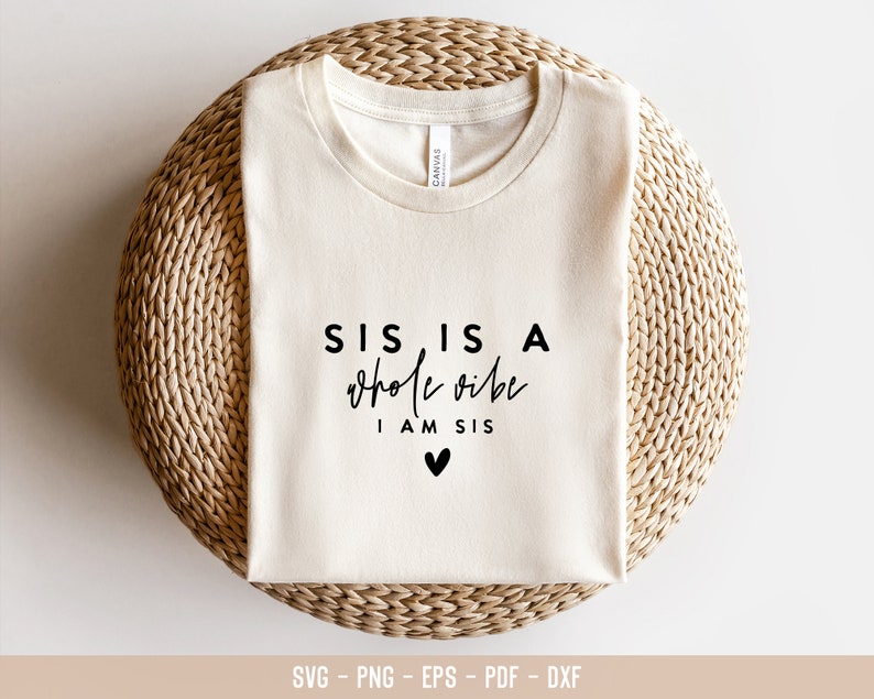 May include: A white t-shirt with black text that reads "SIS IS A whole vibe I AM SIS" with a small black heart below the text.