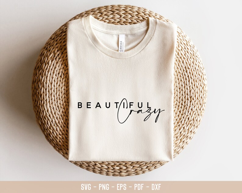 May include: A white t-shirt with the text "BEAUTIFUL crazy" printed on it. The shirt is folded and placed on a woven straw mat.