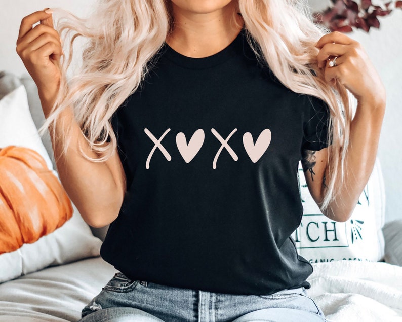 May include: Black t-shirt with a pink graphic of the letters "XOXO" with hearts in place of the "O"s.