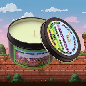 May include: A green soy wax candle in a black tin with the text "SLAPS CANDLES" and "MINE WORLD" in white. The candle is 8 oz and has a 40 hour burn time. The candle is labeled "COCONUT BANANA VANILLA" and "VIDEO GAME FANATIC".