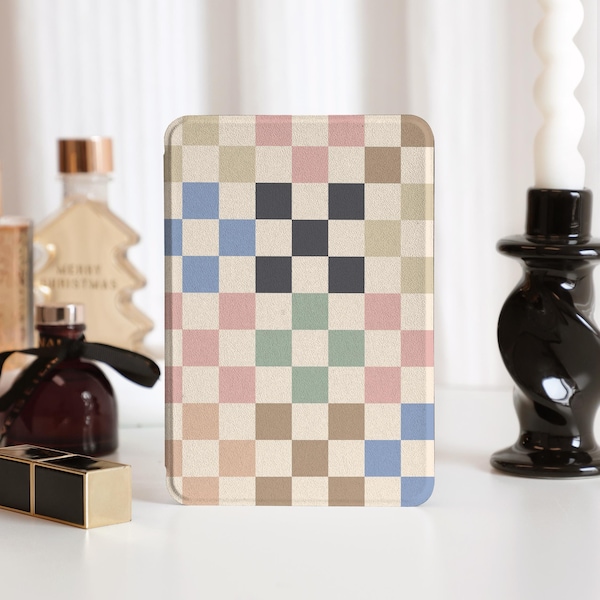 Puede incluir: Una funda para teléfono de forma cuadrada con un patrón de cuadros en tonos beige, rosa, azul y verde. La funda tiene una superficie texturizada.