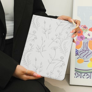 May include: A white notebook with a floral design. The notebook is closed and has a simple, elegant look.