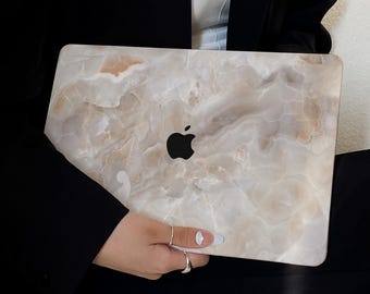 Peut inclure: Un ordinateur portable avec une peau à motif marbré. L'ordinateur portable est fermé et porte un logo Apple sur le couvercle.