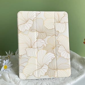 May include: A white tablet case with a floral design. The flowers are outlined in gold and have a white background.