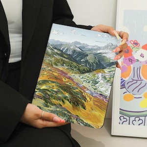May include: A colorful landscape notebook with a mountain scene. The notebook has a textured cover and a brown spine.